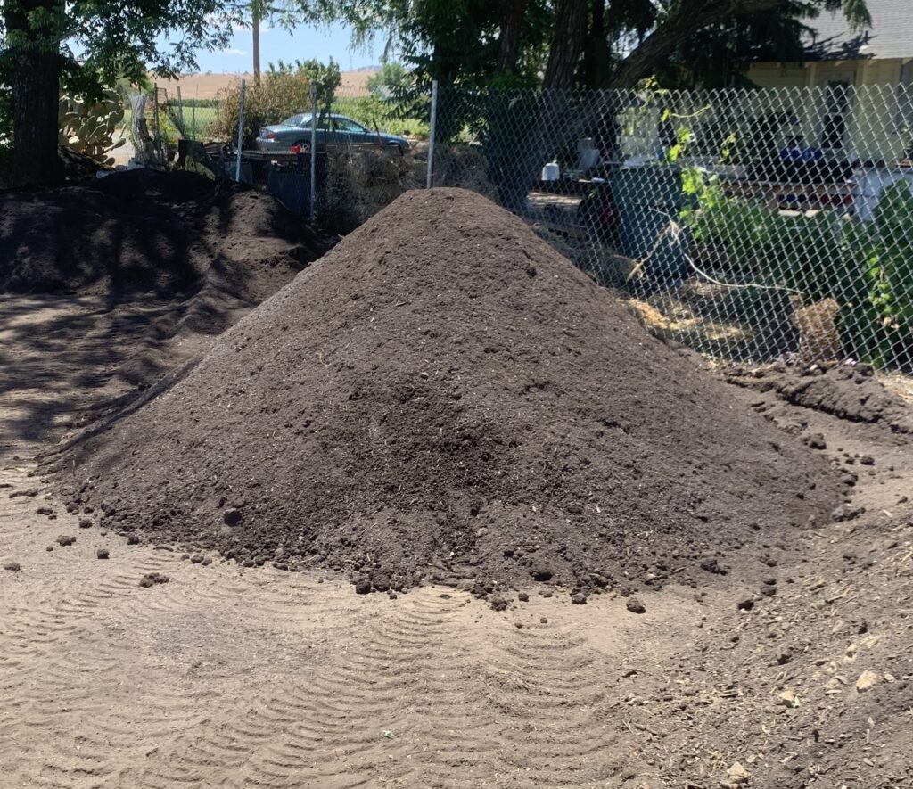 Large pile of finished compost curing before use as a soil amendment in a home composting system.