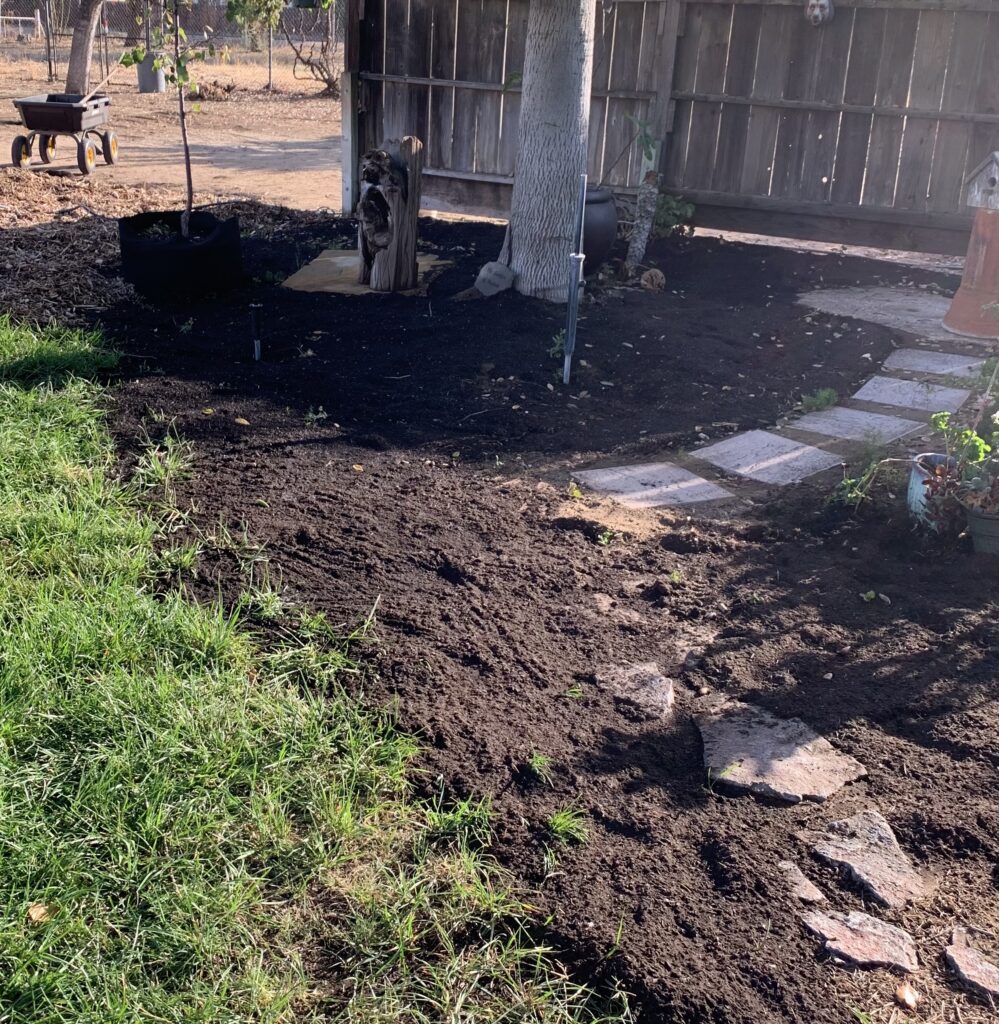 Fresh compost spread over planting areas in the backyard flower garden